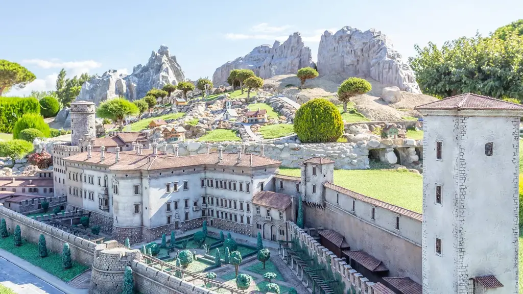Un château historique miniature avec jardin et montagnes rocheuses en arrière-plan à Italia in Miniatura