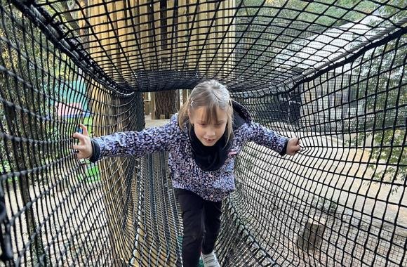 Une petite fille traversant un tunnel de filet suspendu à Riccione Avventura