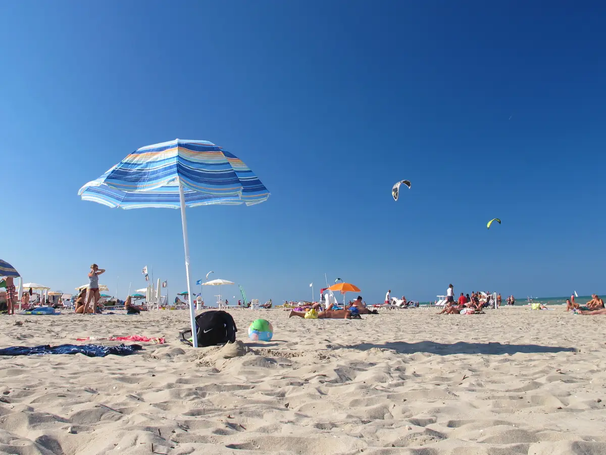Plage libre de Riccione avec un parasol rayé et des cerfs-volants dans le ciel
